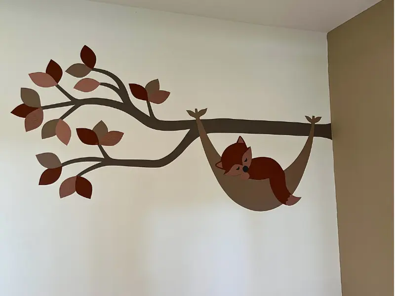 Behangsticker babykamer tak met vosje in hangmat in de kleuren roest en goud.